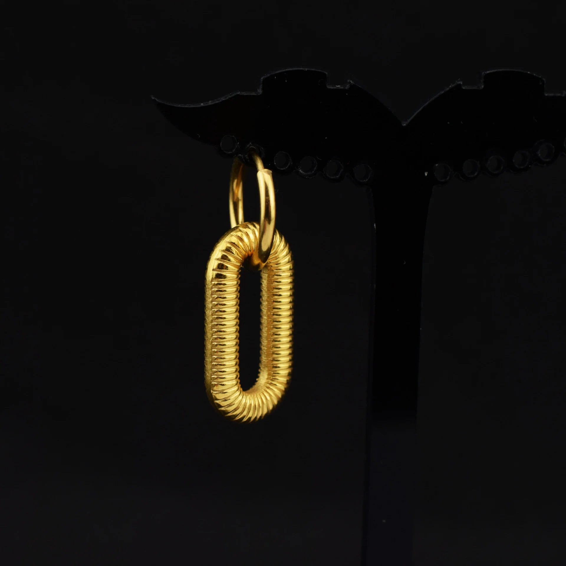 Golden spiral clip-on dangle hoop earrings displayed on black background, featuring textured gold finish and polished metal construction