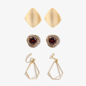 A set of three clip-on earrings. The earrings feature a gold color with one earring having a square shape, and the other two earrings having a geometric layered design.