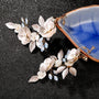 Golden Leaf & Blossom Clip-On Earrings with Pearls displayed on black surface with blue gemstone pouch
