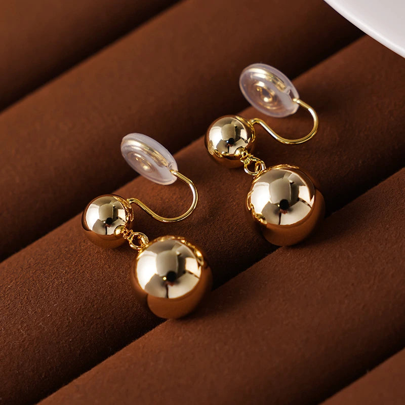 Side angle of Golden Sphere Drop Clip-On Earrings highlighting the 16k gold plating and sleek design.