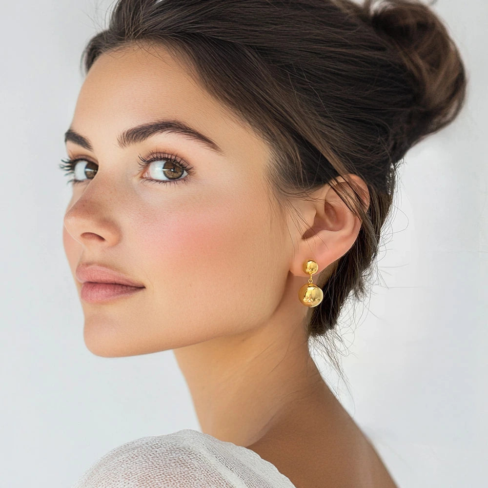 Golden Sphere Drop Clip-On Earrings worn by a model, adding a minimalist yet bold statement.