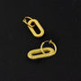 Golden spiral clip-on dangle hoop earrings displayed on black background, showing textured gold finish and oval shape design