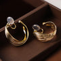 Gold rotating spiral clip-on hoop earrings with moonstone tops displayed on wooden tray, angled side view