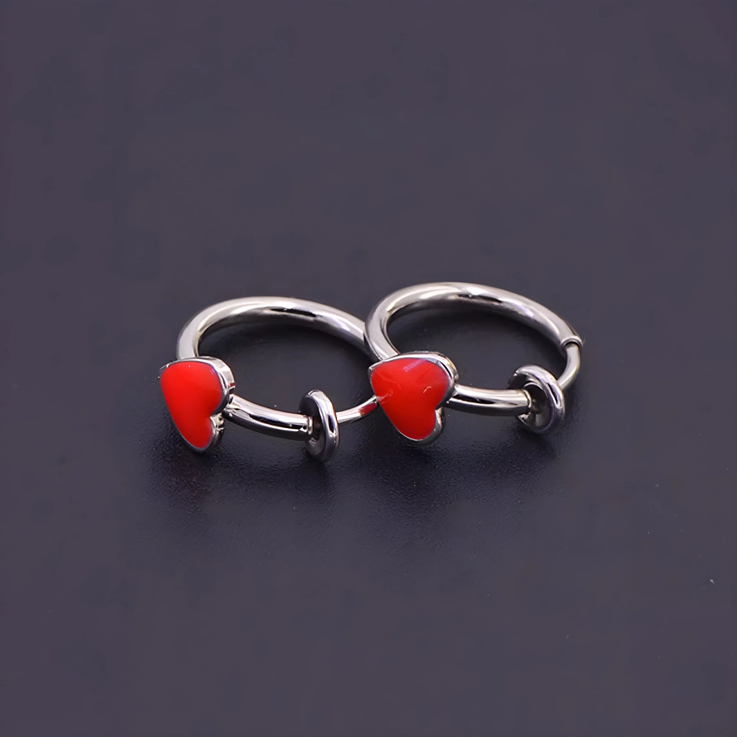 Detailed view of sliding spring-ring clip-on design on silver heart hoop earrings.