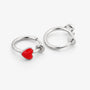 A pair of silver-toned hoop earrings, each featuring a small, polished red heart charm, displayed on a clean white background.