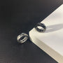 Silver hex cut clip-on hoop earrings displayed on black and white surface, showing geometric design and metallic finish