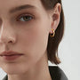 Model wearing 18K yellow gold-plated huggie hoop clip-on earrings.