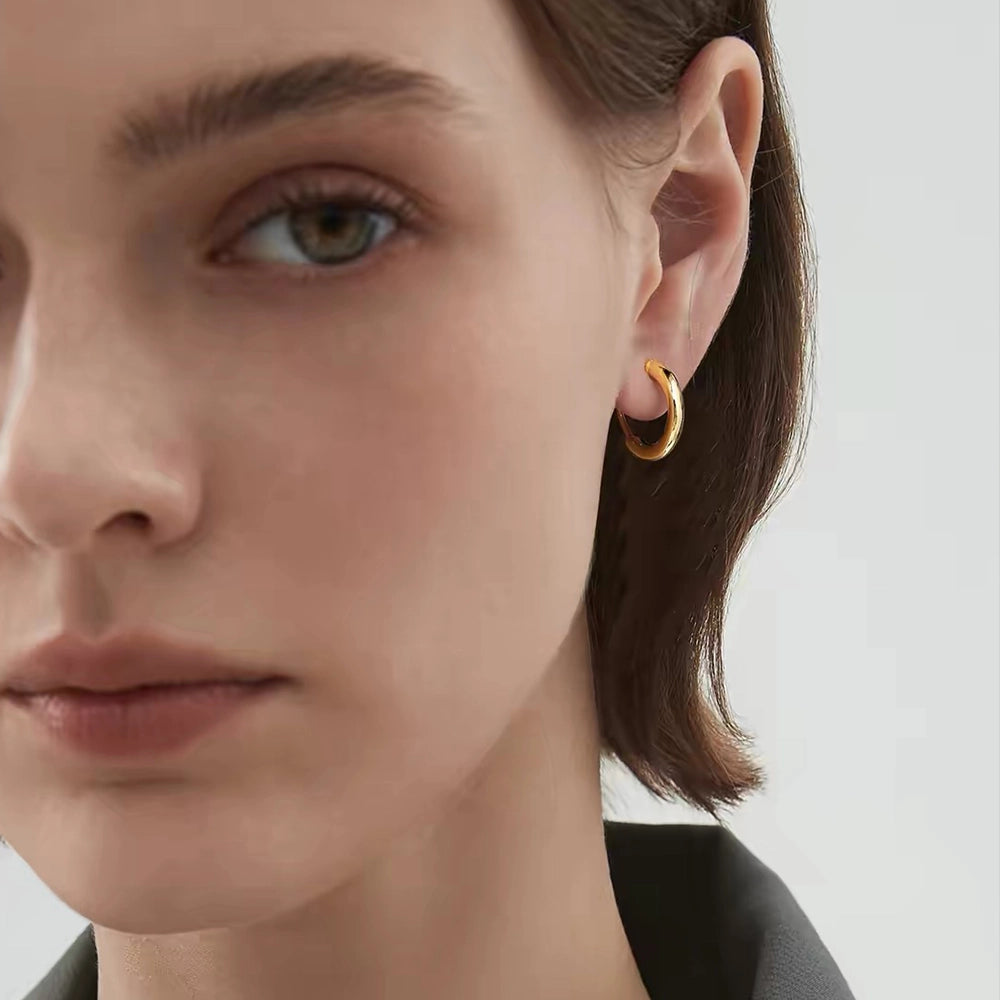 Model wearing 18K yellow gold-plated huggie hoop clip-on earrings.