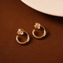 Gold hoop earrings on a brown surface with a white plate in the background