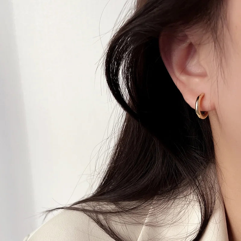 a model wearing gold huggie hoop clip earrings.