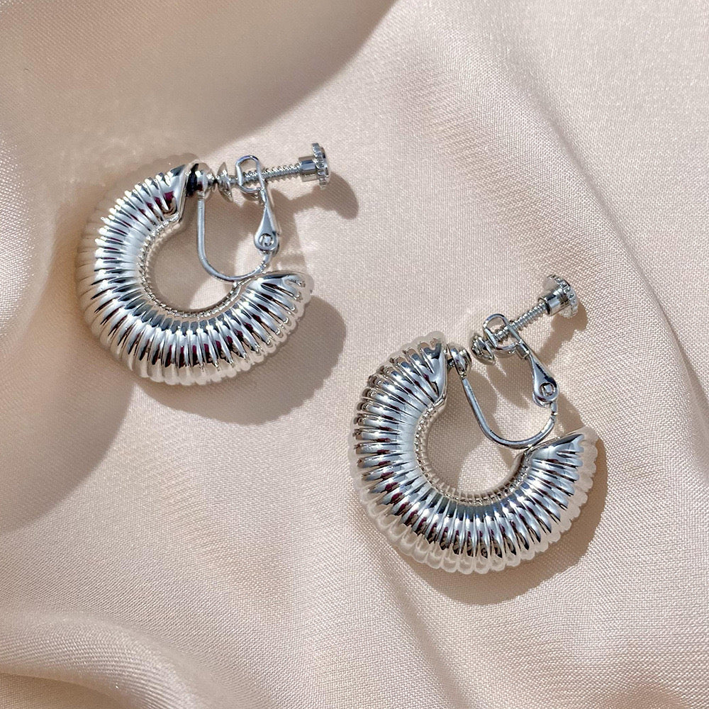 Shimmering silver-tone helix hoop clip-on earrings with a contemporary design, crafted from a silver tone copper alloy and equipped with a screw-back clip-on closure. Ideal for a huggie look without the need for ear piercing.