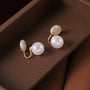 Iridescent pearl clip-on earrings with gold accents displayed on wooden surface, showing lustrous opalescent finish and elegant design from above