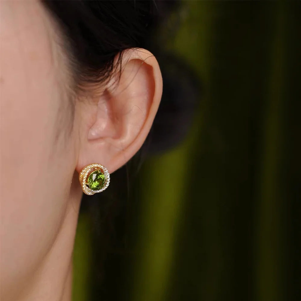 Elegant Large Emerald Zirconia Clip-On Earrings displayed on ear, showing green stone with diamond halo in gold setting, side view