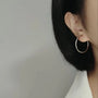 Silver large hoop clip-on earrings side view worn on ear with black hair and white clothing background