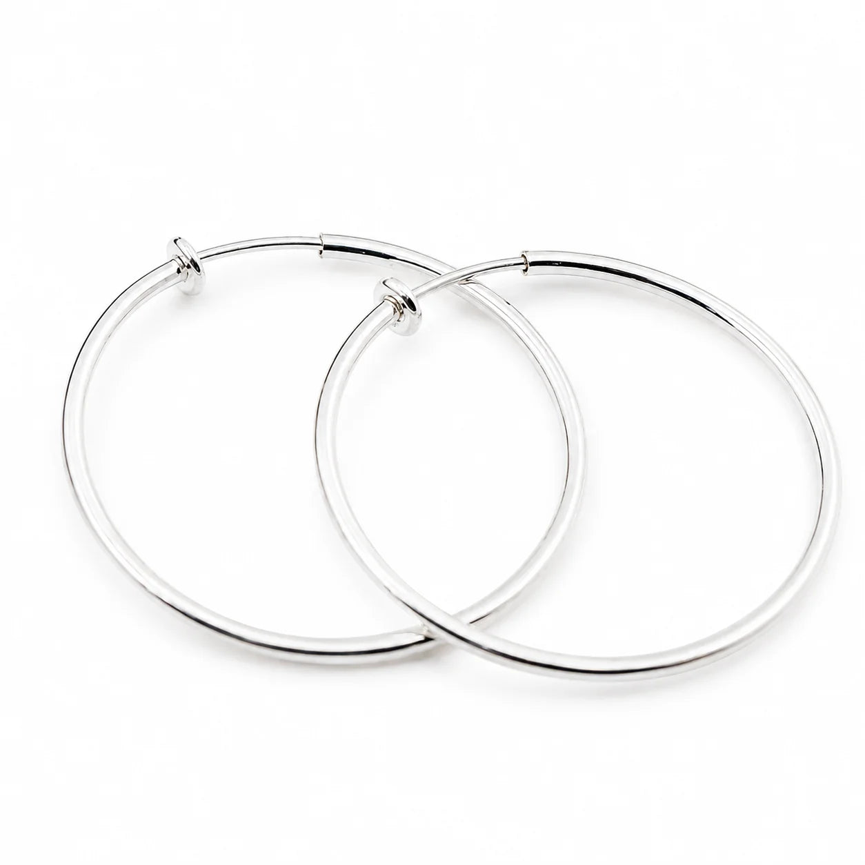Silver large hoop clip-on earrings displayed overlapping on white background showing polished metallic finish