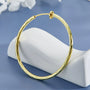 Gold twisted textured hoop clip-on earrings displayed on white stand against blue background