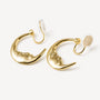 Gold Lunar Face rotating clip-on earrings displayed on white surface, front angle view showing polished finish and cream backing details