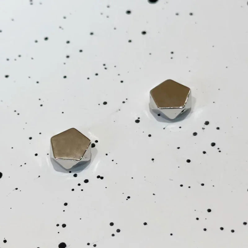 Polygon Magnetic Stud Earrings in Silver displayed at angle on white speckled background showing metallic finish and geometric shape