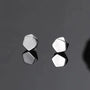 Silver polygon magnetic stud earrings displayed on gray surface showing geometric pentagonal design from front angle