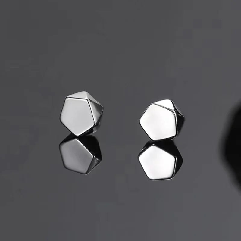 Silver polygon magnetic stud earrings displayed on gray surface showing geometric pentagonal design from front angle