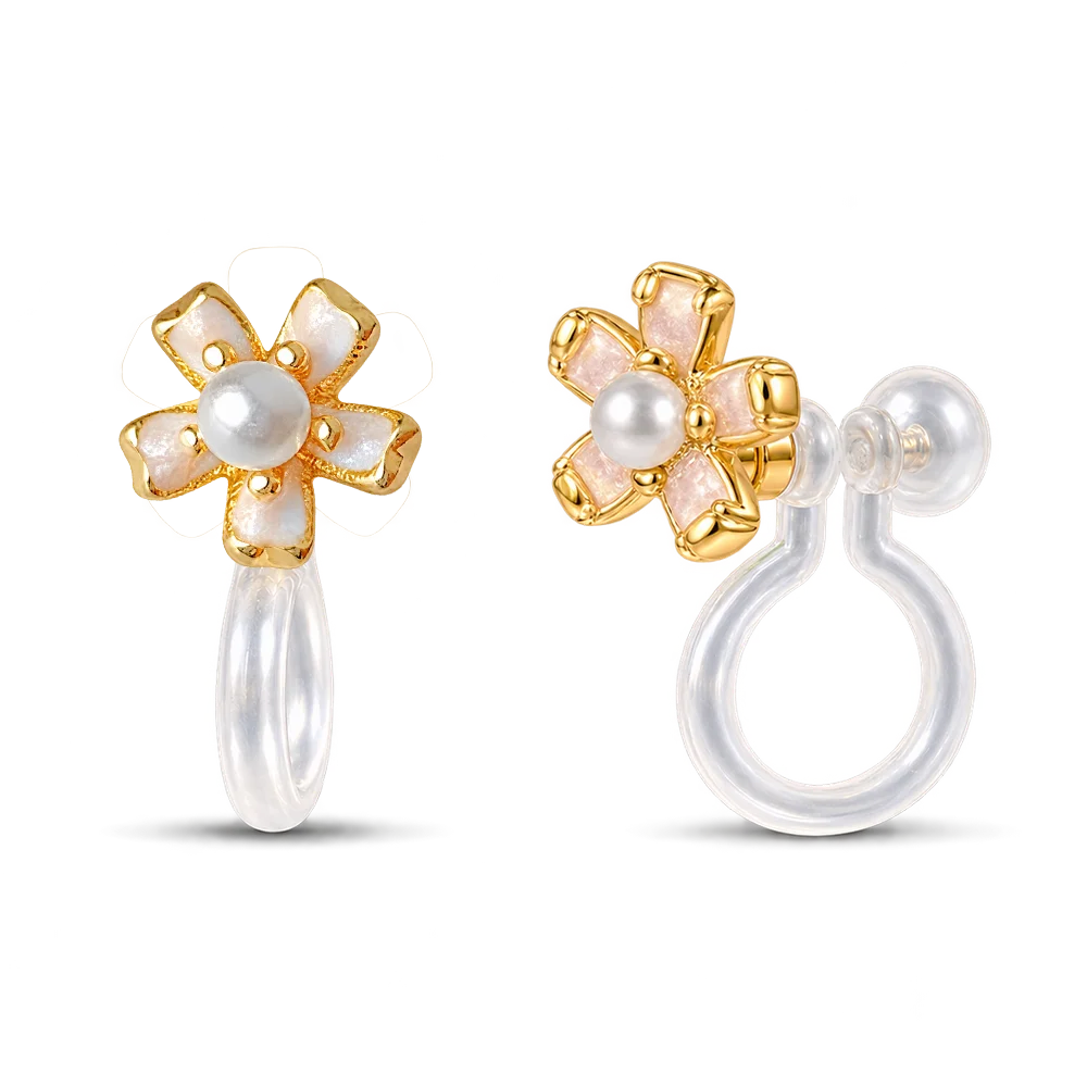 A pair of gold flower-shaped clip on earrings with white pearl centers and iridescent white petal inlays, shown on a clean white background with one earring facing forward and the other showing the side profile.