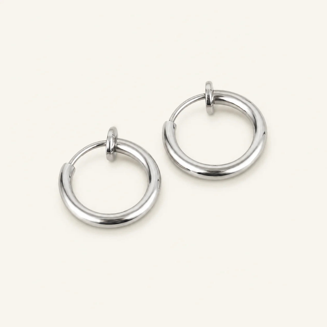 Silver mini hoop clip on earrings angled view on dark background showcasing polished metallic finish