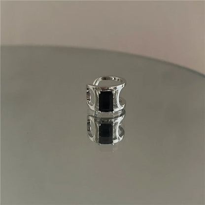 Minimalist Black Zircon Band Ear Cuff displayed on a reflective surface.