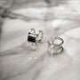 Silver minimalist white zirconia band ear cuff displayed on marble surface showing rectangular stone detail and polished metal finish