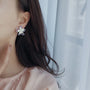 Pastel Petals Mismatched Clip-On Earrings worn on ear, side view, white flower design with purple accents