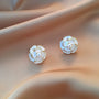 White Camellia enamel clip-on earrings with pearl centers displayed on skin, showing detailed flower design from front angle