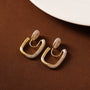 Pavé square gold clip-on hoop earrings displayed on brown background with crystal embellishments