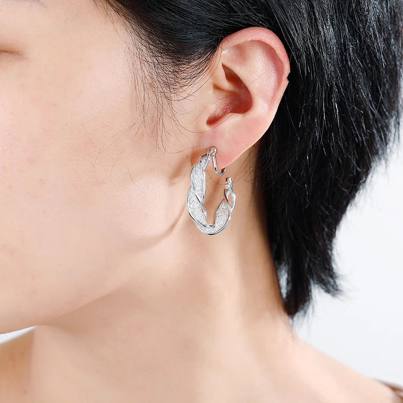 Silver Glimmering Lattice Twist Clip-On Earrings side view on model with black hair
