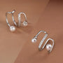 Silver pearl and zirconia double-band ear cuffs displayed on tan skin, showing elegant curved design with pearl accents