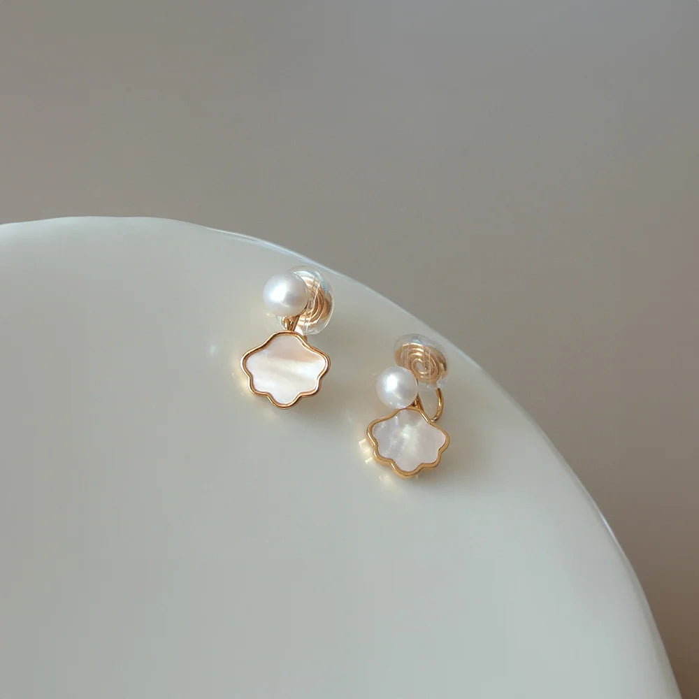 Genuine pearl and shell clip on earrings in gold with white mother-of-pearl flower charms on ceramic dish