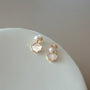 Vue détaillée d'une boucle d'oreille à clip en perle et coquillage, mettant en valeur la perle blanche lustrée et l'élégante nacre dans une monture plaquée or.