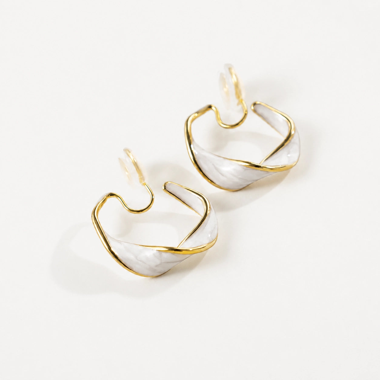 Pearlescent Wave Clip-On Hoop Earrings in gold and iridescent white, angled view