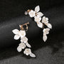 White Petal Pearl Cascade clip-on earrings displayed on black background, showing elegant floral design with gold-tone hardware and pearl accents