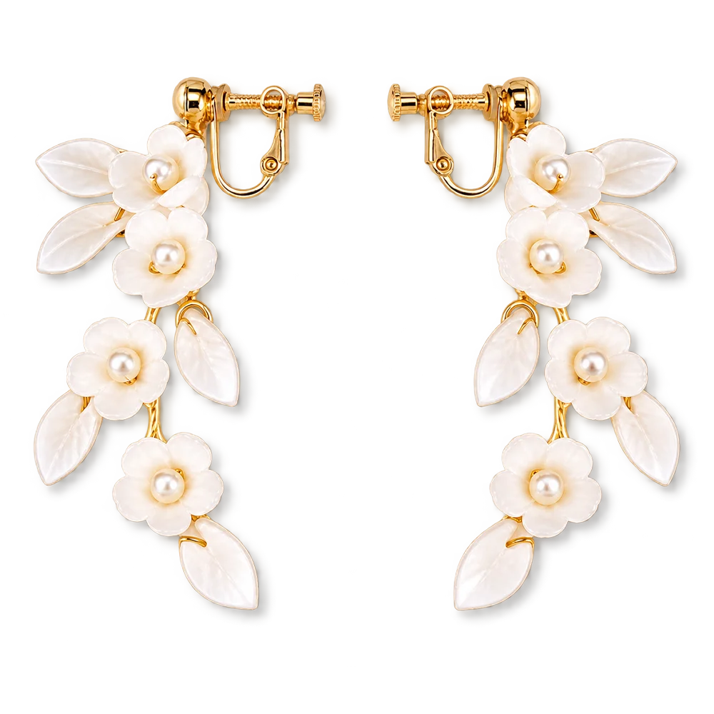 A pair of gold-tone drop earrings featuring white enamel flowers with pearl centers and leaf-shaped enamel details, shown on a plain white background.