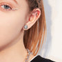 A female model wearing a single matte silver round magnetic stud earring, showcasing its unisex appeal.