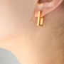 Gold rectangle clip on hoop earrings side view worn on ear, geometric design