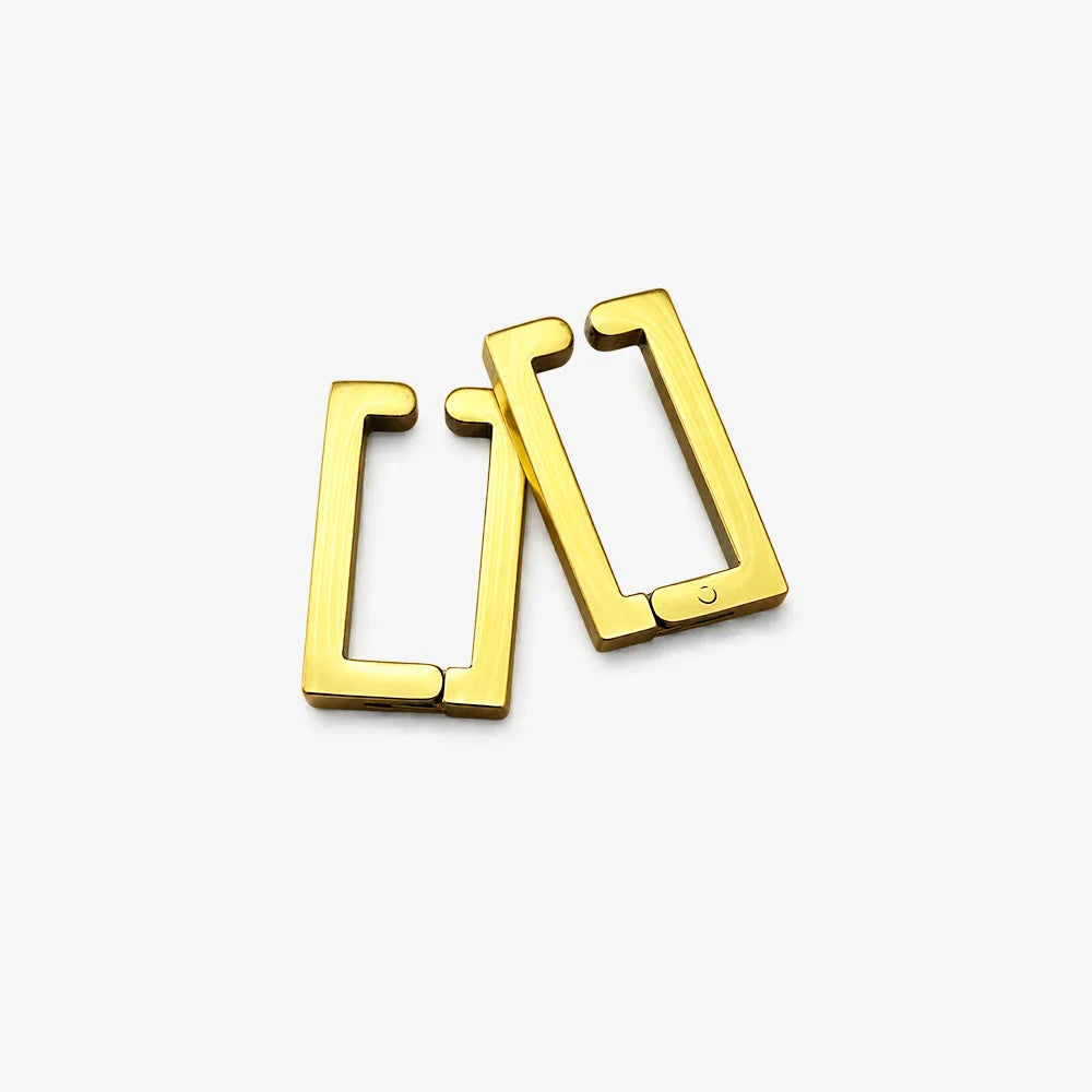 A pair of gold geometric clip-on earrings with a modern open-frame design, displayed on a clean white background.