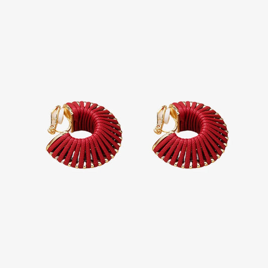 Pair of red leather spiral clip-on hoop earrings on fabric