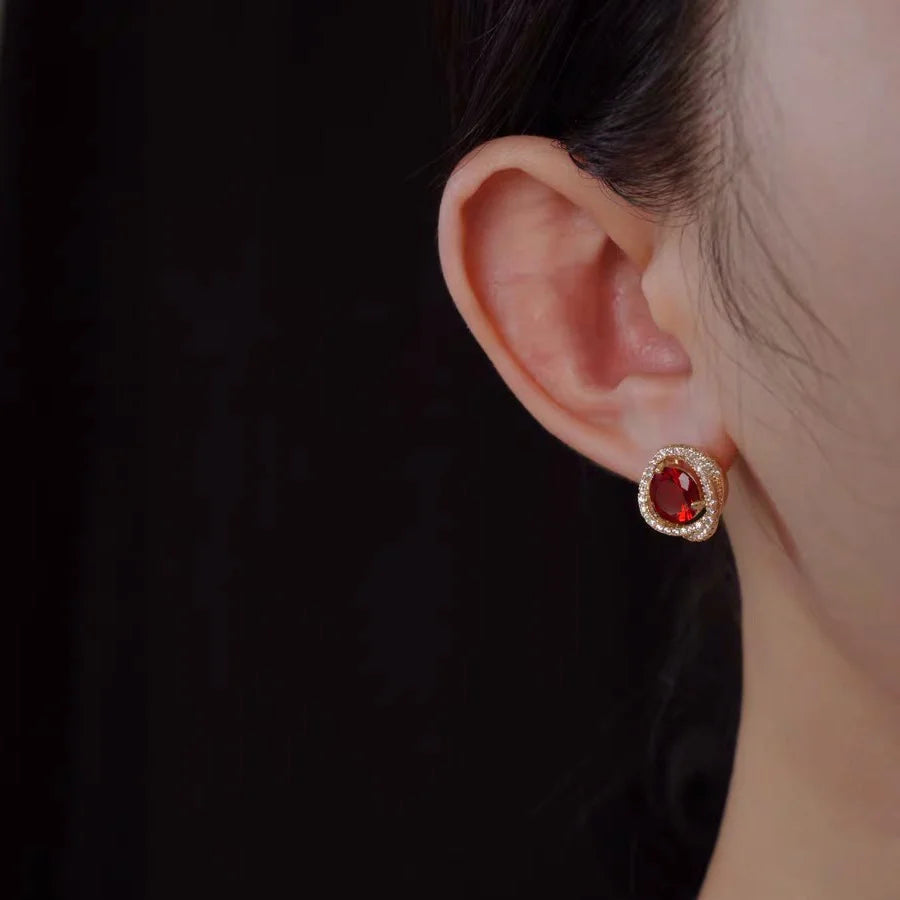 Large ruby zirconia clip-on earrings with gold trim shown on ear, side profile view, elegant design