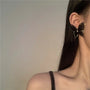 Black silhouette butterfly wings clip-on earrings worn on ear, side view showcasing delicate design and metal accents