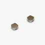 A pair of small geometric stud earrings with faceted hexagonal shapes, featuring a warm bronze-silver face and a polished silver-colored edge, set against a plain light gray background.