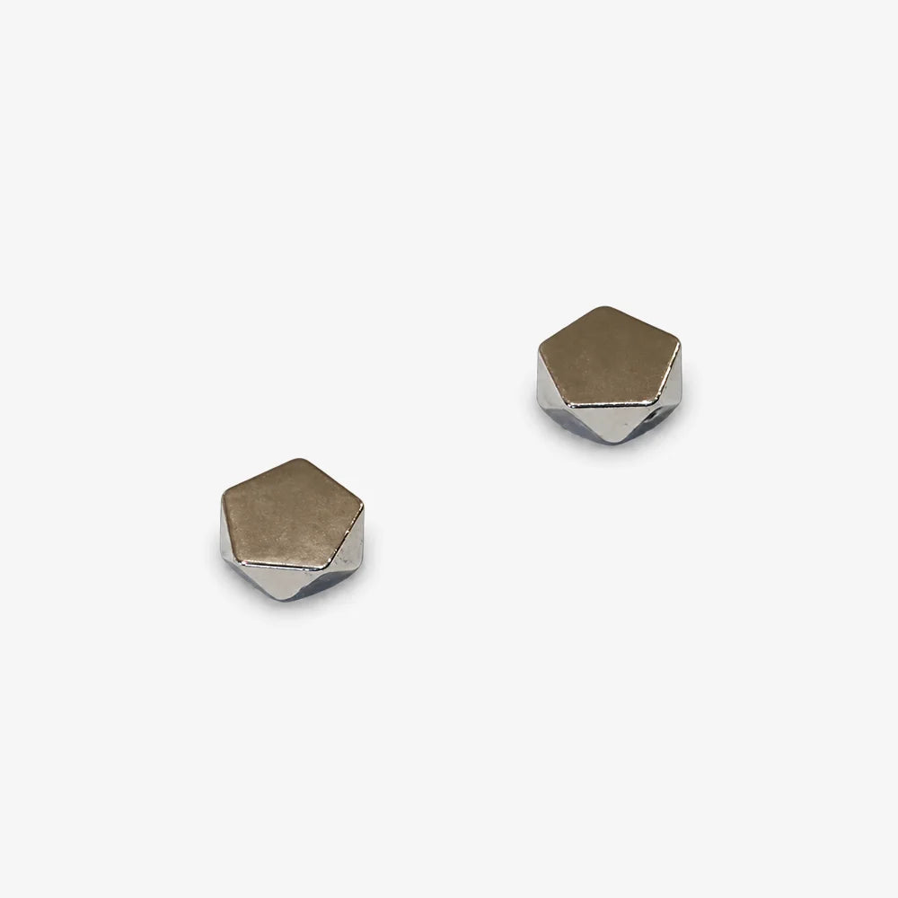 A pair of small geometric stud earrings with faceted hexagonal shapes, featuring a warm bronze-silver face and a polished silver-colored edge, set against a plain light gray background.