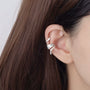 Silver snake ear cuff with zirconia accents worn on ear, side view showing detailed design and sparkle
