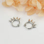 Silver spike hoop clip-on earrings displayed front view on white background with peach flowers