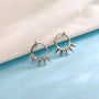 Silver spike hoop clip-on earrings displayed on light blue surface against white background