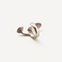 A silver-toned ring with a sculptural, organic shape and textured pavé-set details, photographed on a clean, light off-white background.